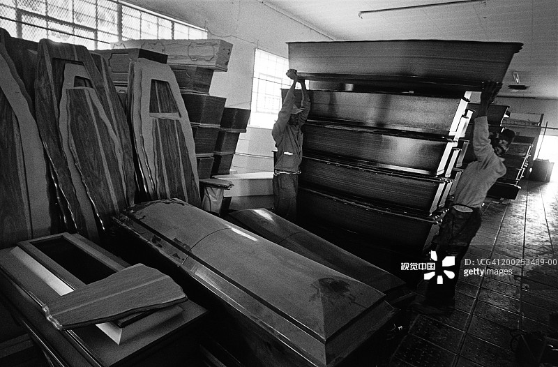 在南非索韦托的棺材厂里，男人们正在搬运棺材图片素材