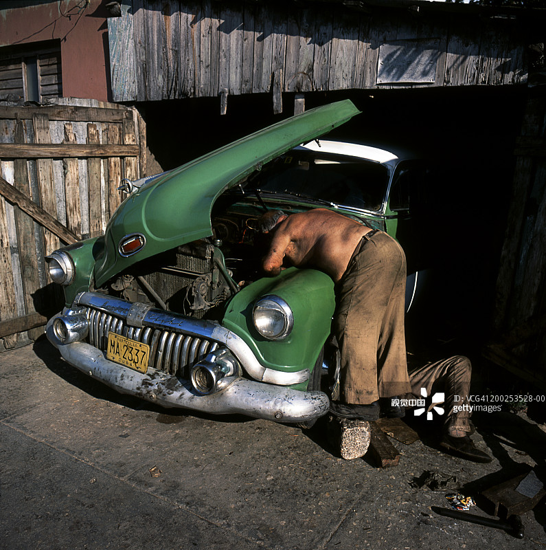 古巴男子在马坦萨自家屋外修理一辆老款别克图片素材