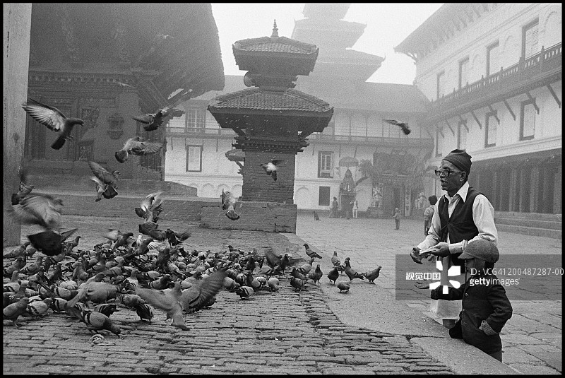 尼泊尔加德满都杜巴广场：男子和儿童喂鸽子（黑白）图片素材