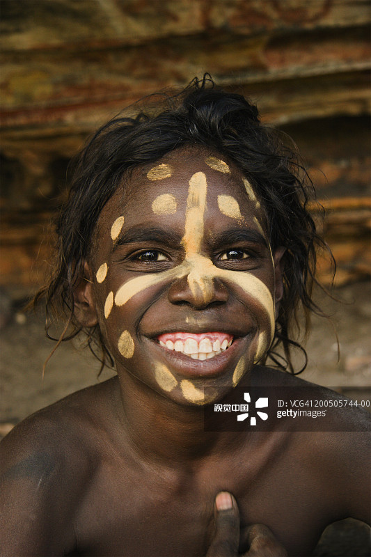 脸上涂着油彩的土著男孩的微笑特写图片素材