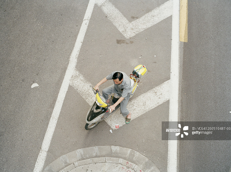 在十字路口骑摩托车的男人（高角度视角）图片素材
