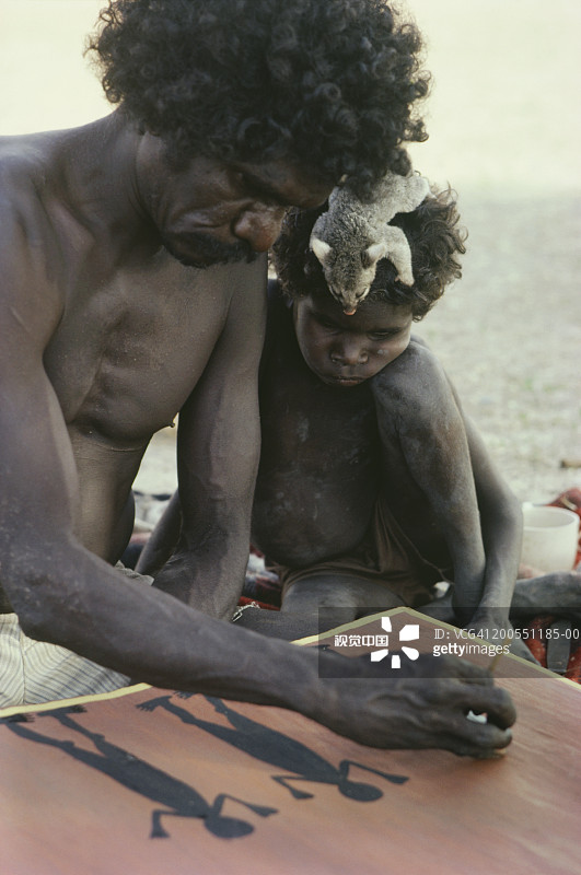 澳大利亚阿纳姆地，澳洲原住民男人绘画，男孩观看图片素材