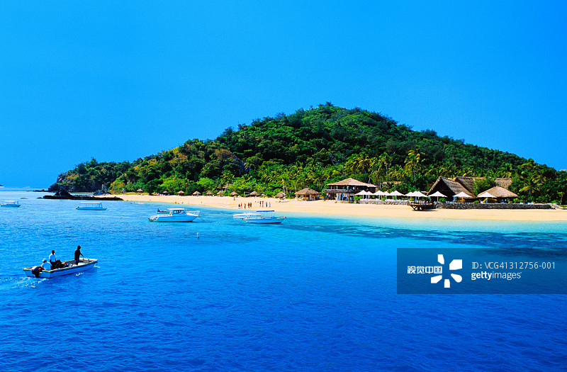 斐济Castaway岛，带小屋和棕榈树的海滩，船只驶近图片素材