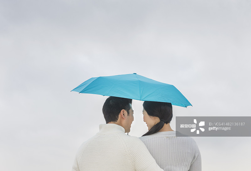 情侣在雨伞下拥抱图片素材