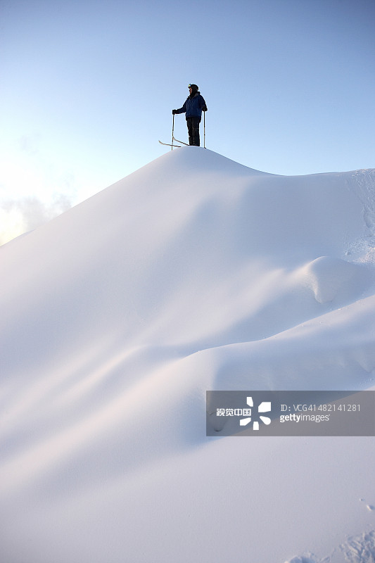 站在雪山顶上的白人滑雪者图片素材