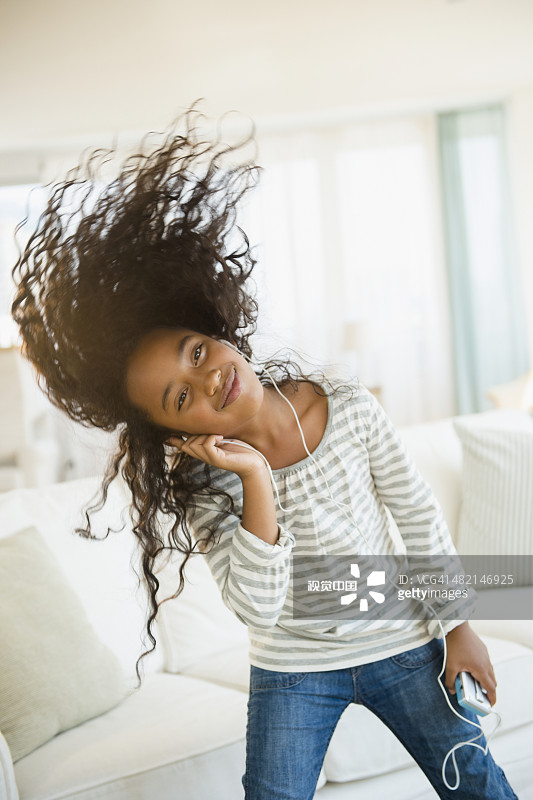 在客厅里戴着耳机跳舞的混血女孩图片素材