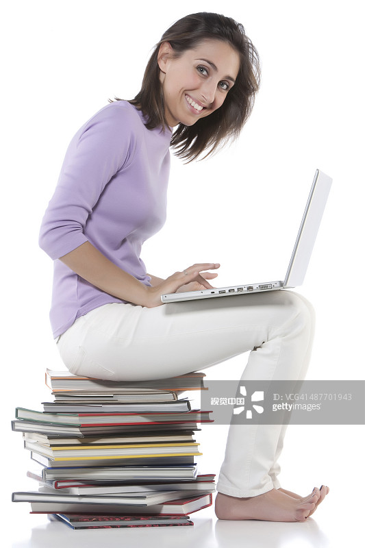 女人在书堆上使用笔记本电脑图片素材