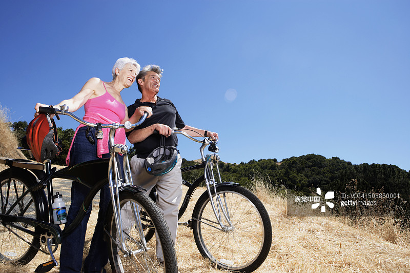 年长的白人夫妇在山顶上推着泥土自行车图片素材