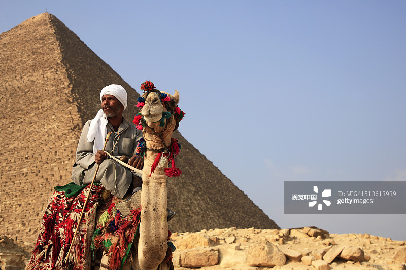 骑着骆驼在胡夫金字塔旁的男人图片素材