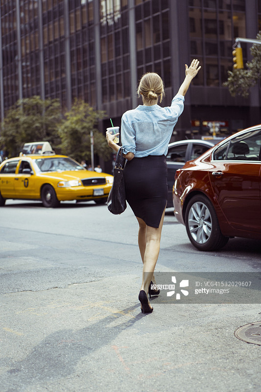 在城市街道上招出租车的白人女性图片素材