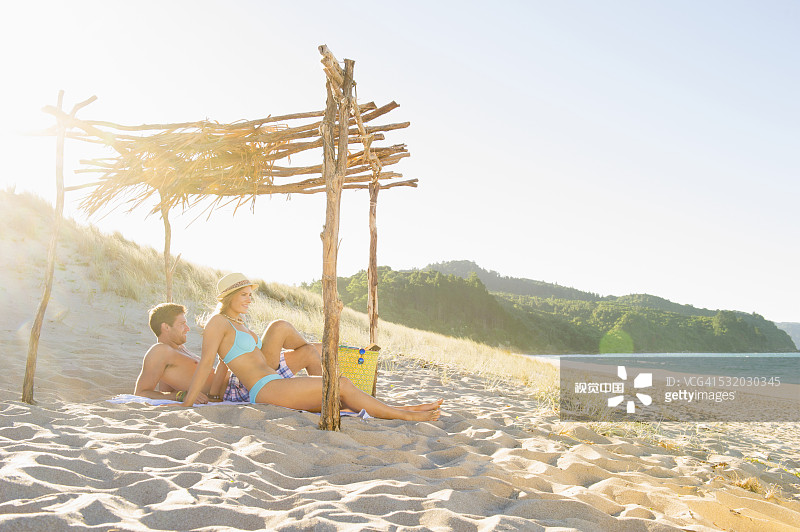 一对白种夫妇在沙滩上的木质天篷下放松图片素材