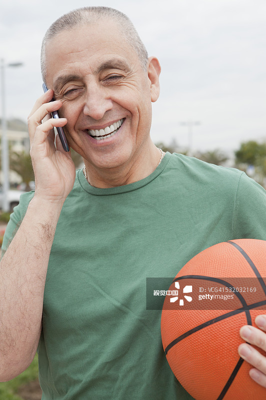 西班牙裔老人拿着篮球在打电话图片素材