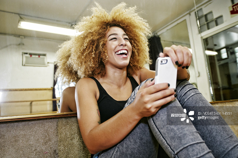 在工作室使用手机的西班牙裔舞蹈演员图片素材