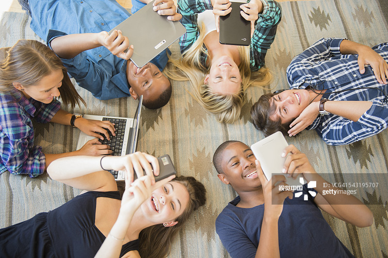 青少年躺在地板上使用电子设备图片素材