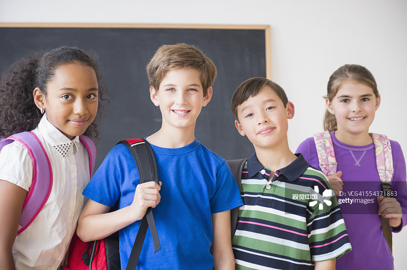 在黑板前背着背包的微笑学生图片素材
