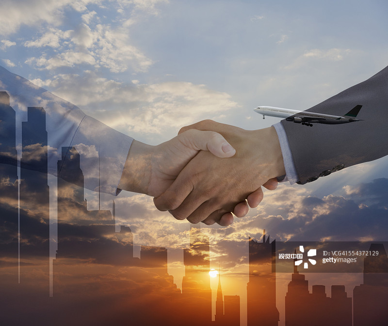 城市天际线剪影下的商务人士握手图片素材