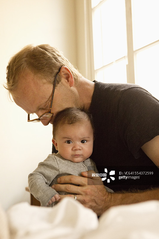 父亲在床上亲吻男婴图片素材