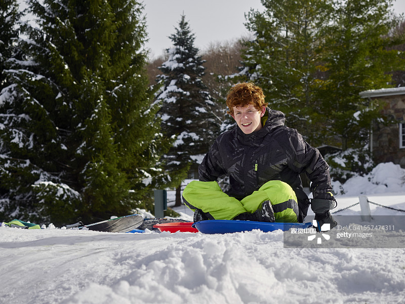 在雪山上玩雪橇的白人少年图片素材