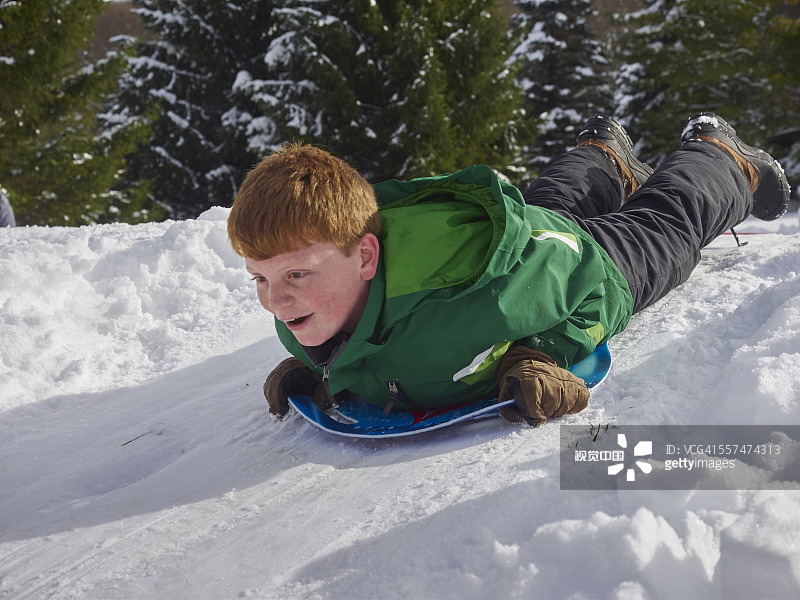 一个白人男孩在雪山上拉雪橇图片素材
