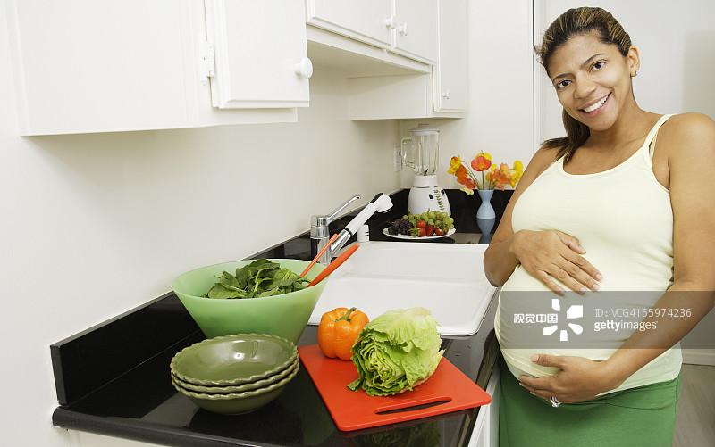 孕妇在厨房抚摸腹部图片素材