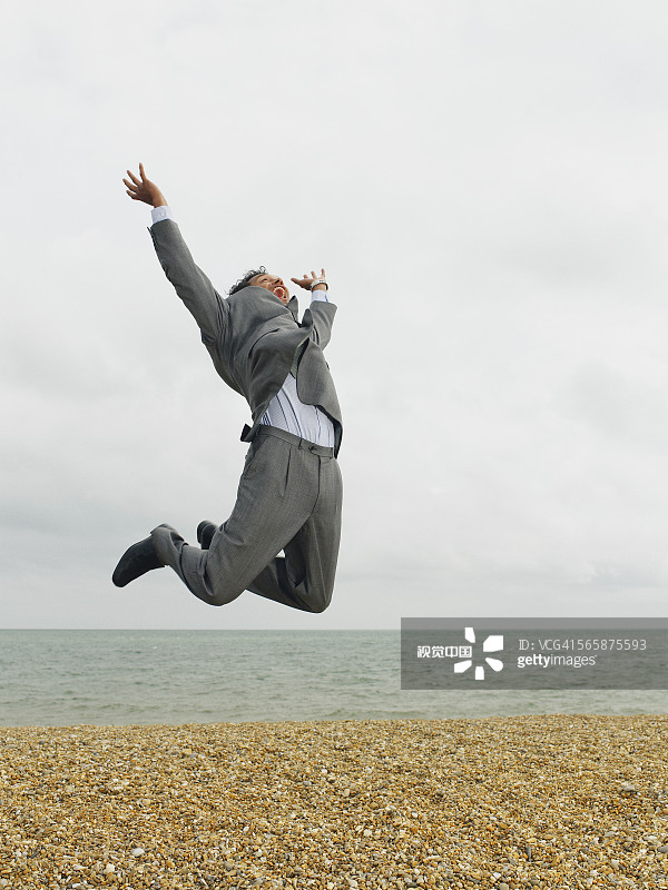 在海滩上高兴跳跃的商人图片素材
