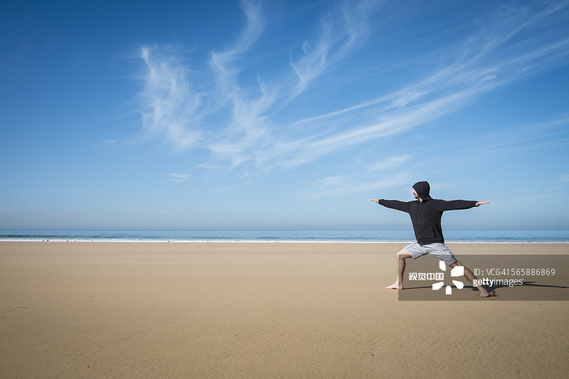 在海滩上练习瑜伽的白人男人图片素材
