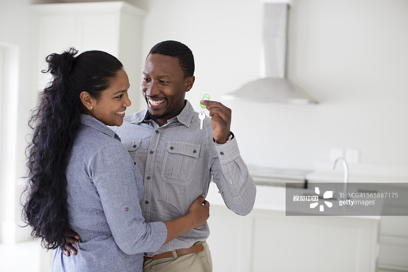 情侣在新家拥抱并拿着钥匙图片素材