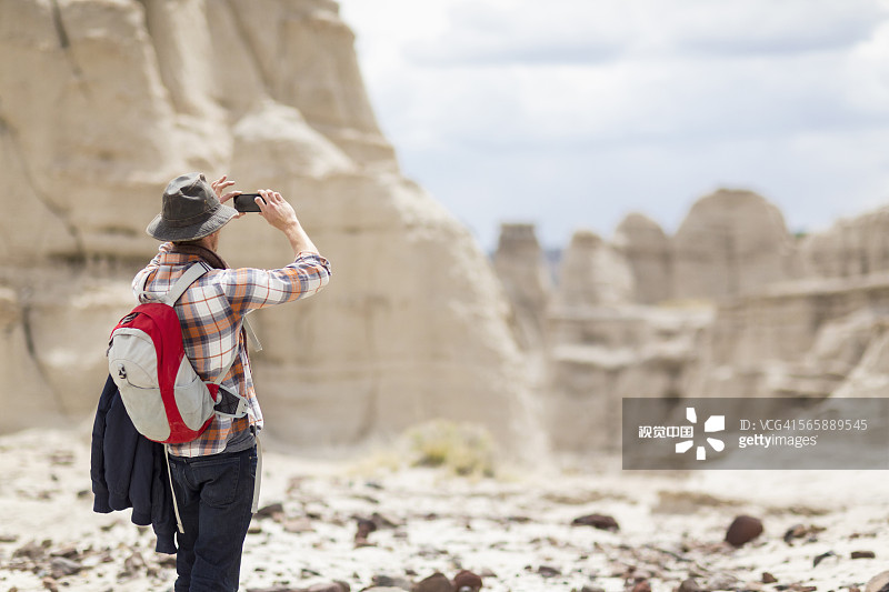 白人徒步旅行者拍摄沙漠岩层图片素材
