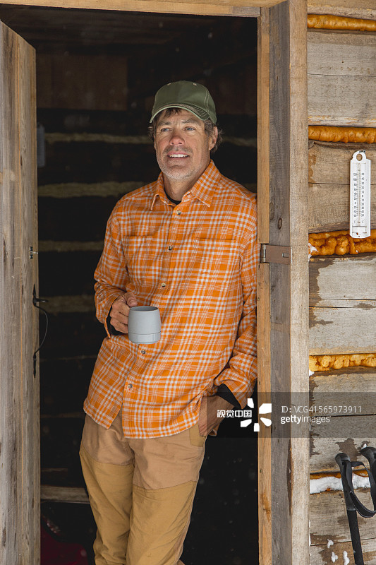 在小木屋门口喝咖啡的混血男人图片素材