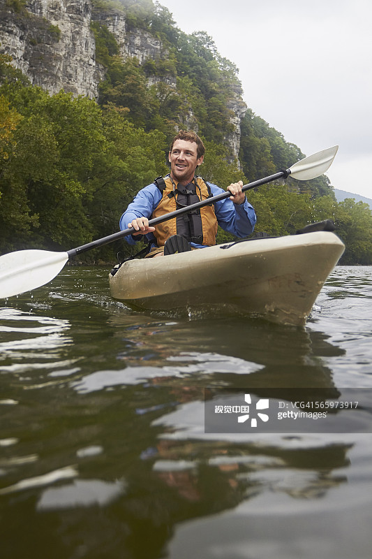 白人男子在偏远的河流上划皮划艇图片素材