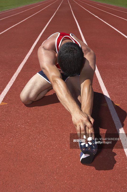 正在伸展身体的男子田径运动员图片素材