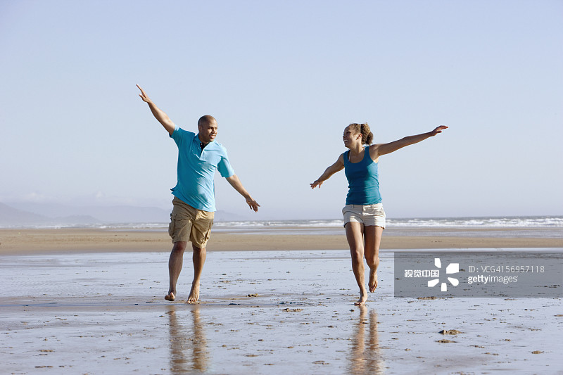 情侣在海滩上张开双臂玩耍图片素材