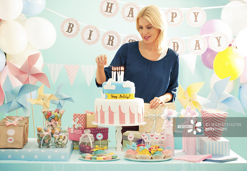 女人在聚会上点燃生日蛋糕上的蜡烛图片素材