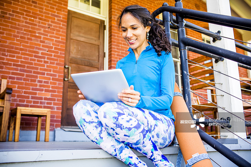 拉美裔女子在门廊上使用平板电脑图片素材