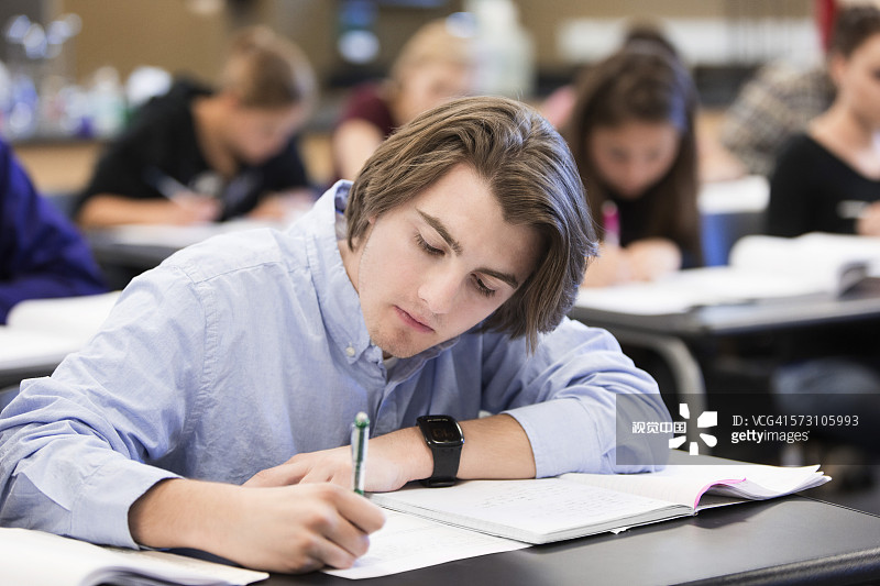 在教室的桌子上写作的白人学生图片素材