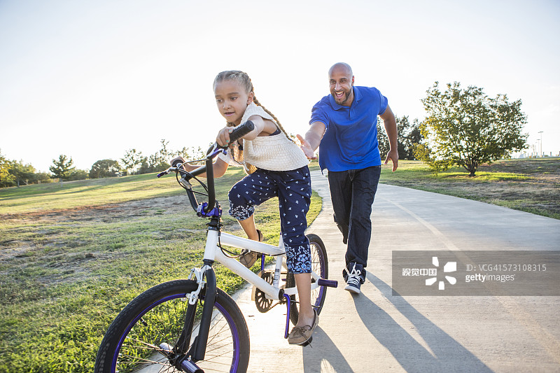 父亲在公园教女儿骑自行车图片素材