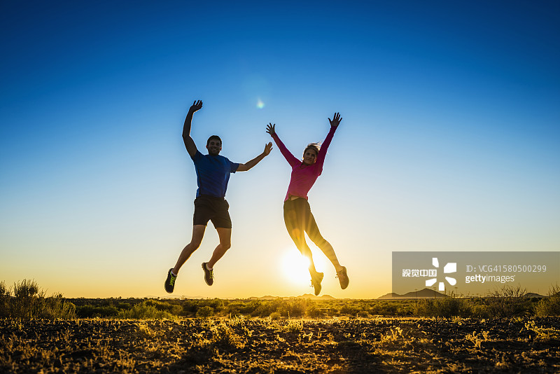 白人情侣在偏远田野欢呼跳跃图片素材