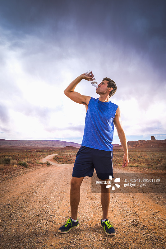 白人运动员在沙漠中喝水图片素材