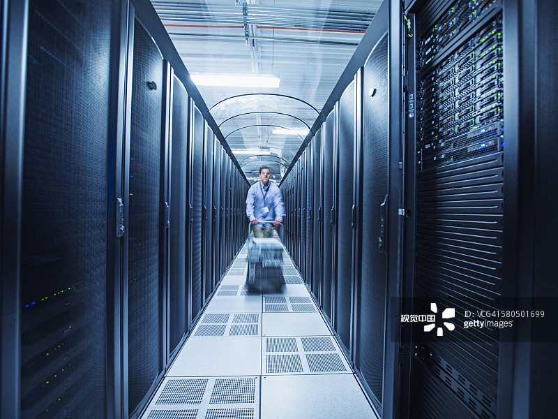 在服务器机房里推车的西班牙裔技术员图片素材