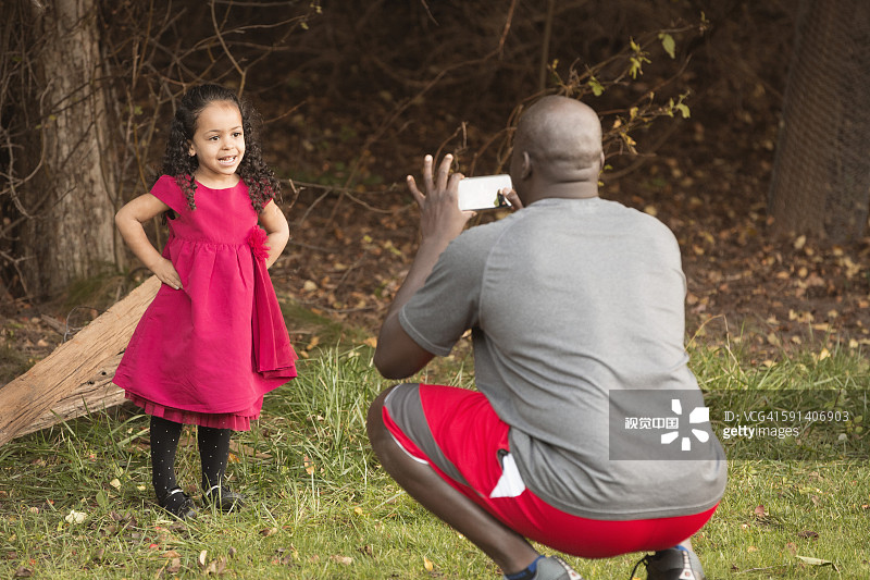 父亲在聚会上给穿着派对礼服的女儿拍照图片素材