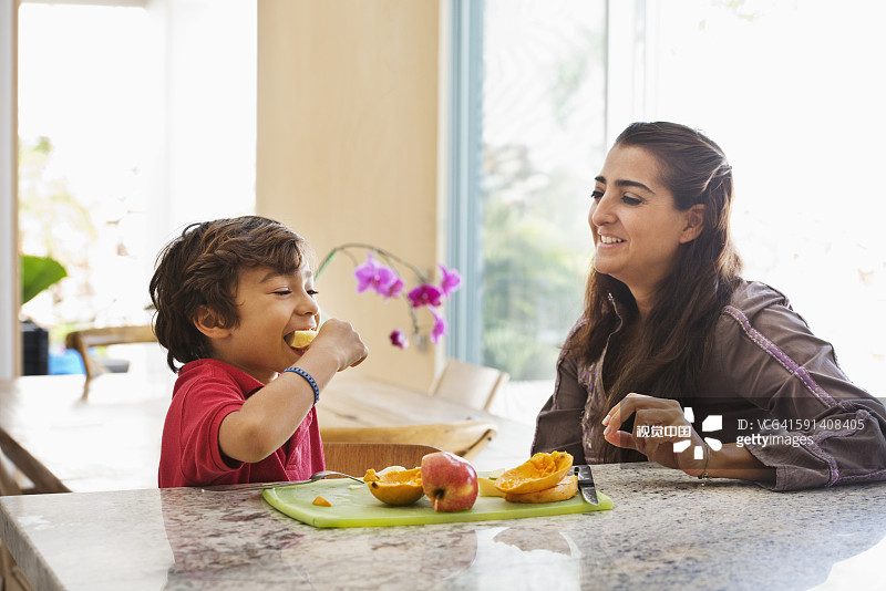 西班牙裔母亲和儿子在厨房吃水果图片素材