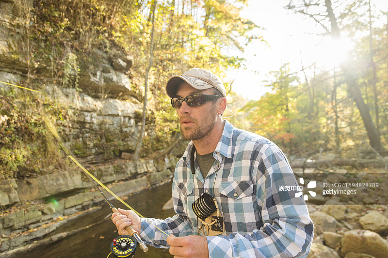 一个白种人在森林小溪里钓鱼图片素材