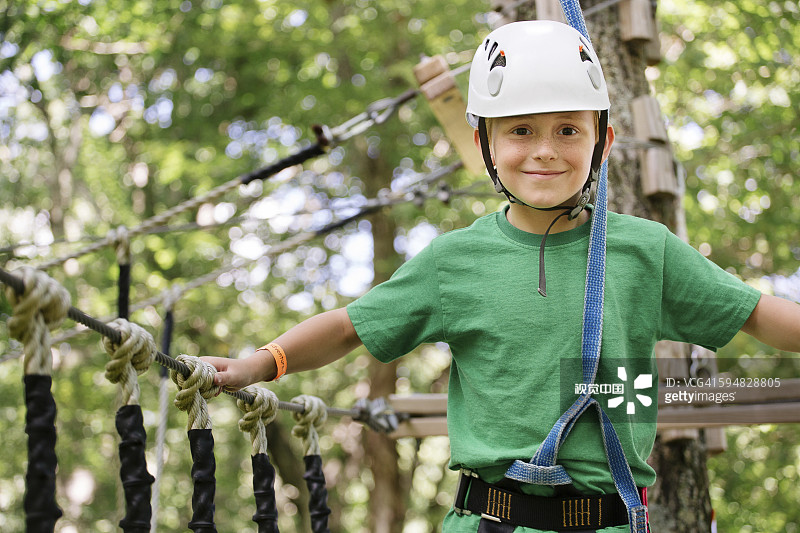 白人男孩在绳索桥上保持平衡图片素材