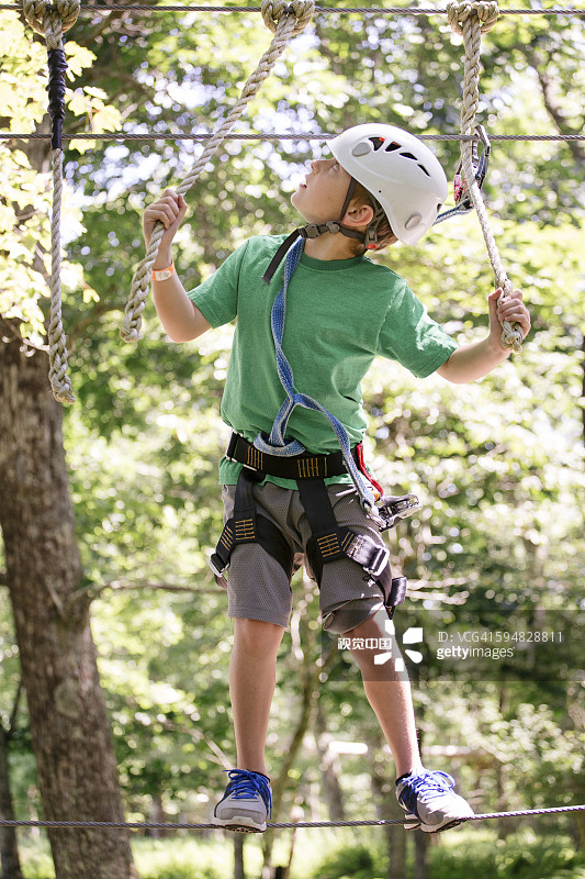 白人男孩在森林里的绳索上保持平衡图片素材