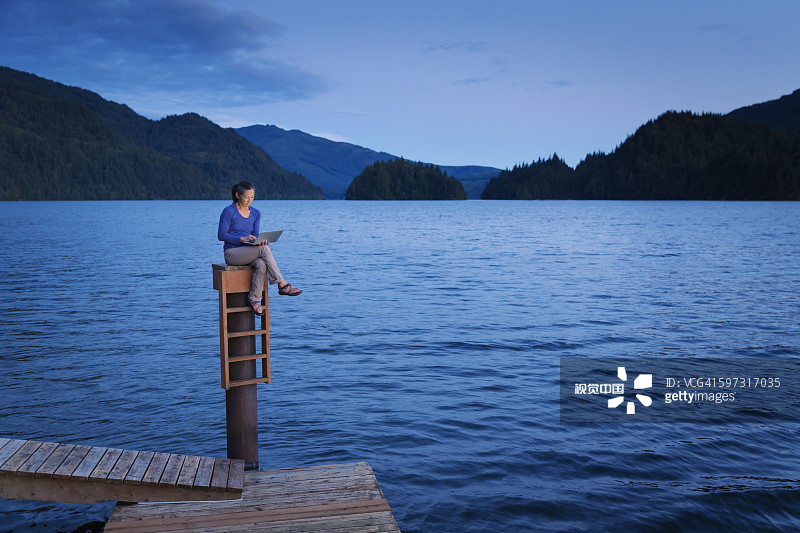 一个日本女人坐在湖边的木码头上图片素材