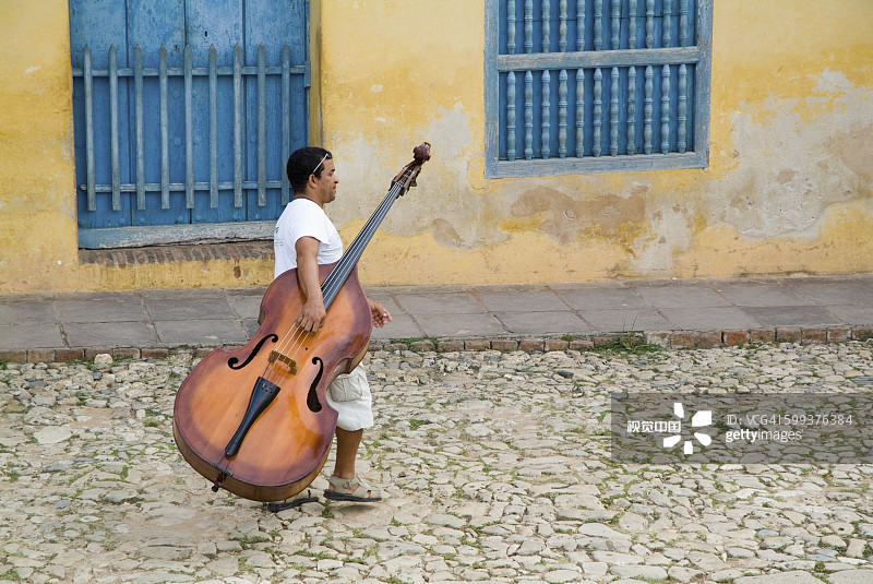 男人在古巴特立尼达西蒙玻利瓦尔大街上 carrying a cello图片素材