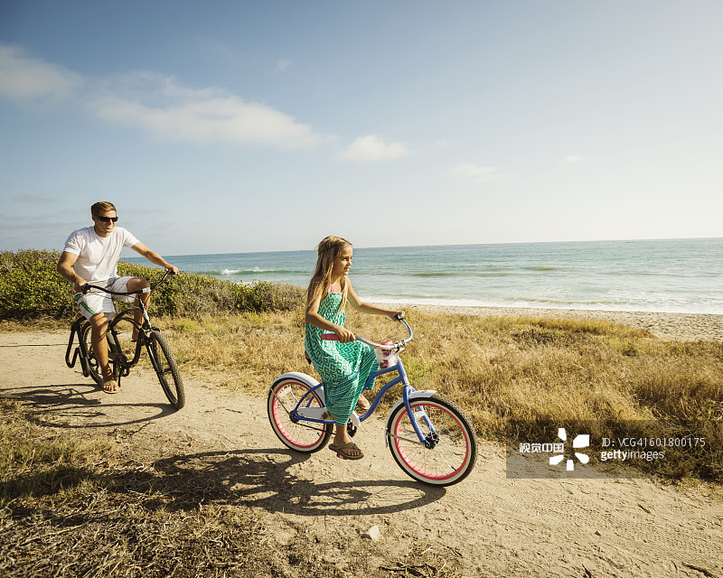 白人父亲和女儿在海滩上骑自行车图片素材