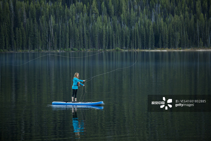 在河中桨板上钓鱼的白人女性图片素材