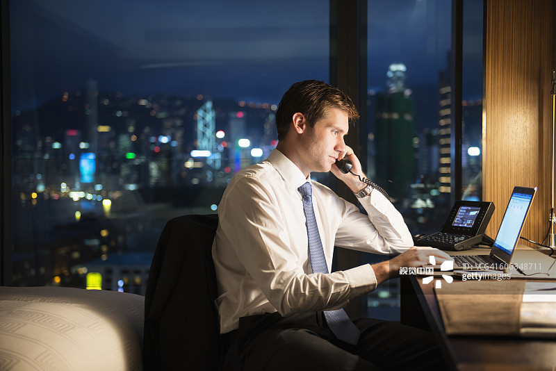 在酒店房间工作到深夜的白人商人图片素材