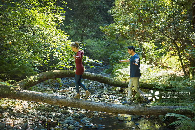 西班牙裔夫妇在森林中的原木上保持平衡图片素材